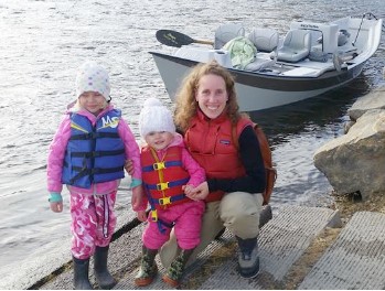 Julie Fleury with her daughters by a boat in the river